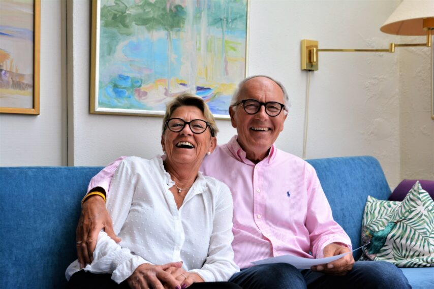 Trygve og kona Barbara sitter i sofaen og ler mot kamera
